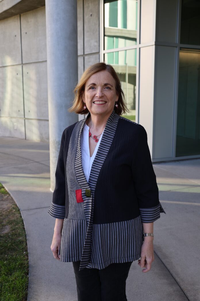 Professor O'Connor stands smiling at Humanities Gateway.
