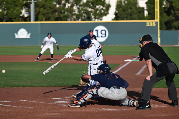 12-bsb-Xuanying A UC Irvine batter swings at a ball with a runner on first base