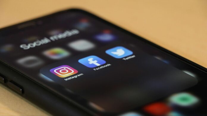 An iPhone with a social media folder open of Instagram, Facebook, and Twitter,