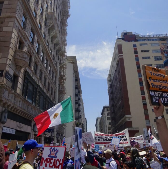 A Mexican flag emerges from a large crowd of anti-ICE posters in downtown Los Angeles.