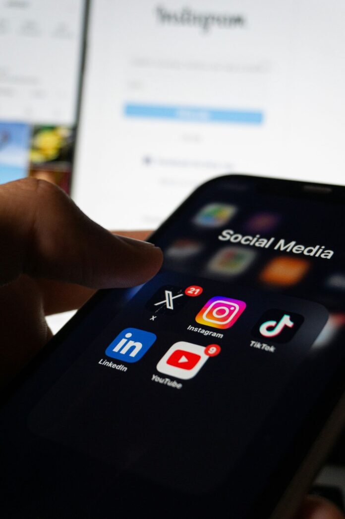 A thumb hovering over an iPhone app folder titled "Social Media".